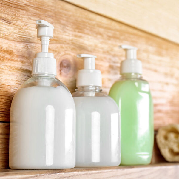 Three bottles  filled with white and green product on a wooden shelf