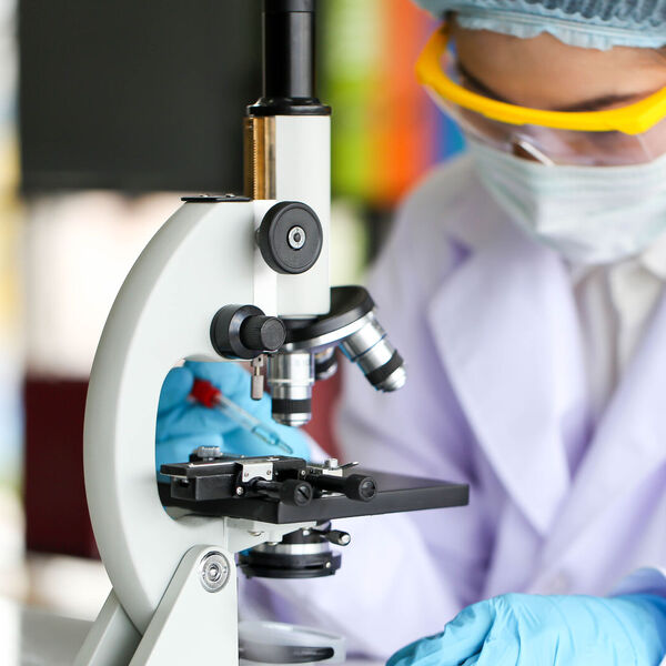 Biochemist looking in microscope