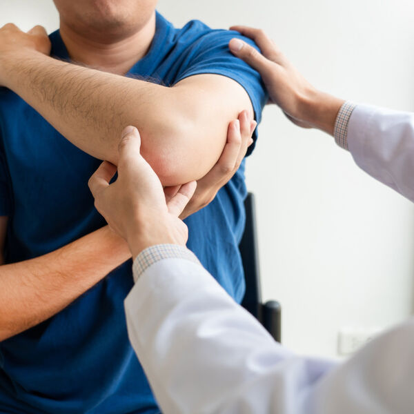 Chiropractor looking at man's arm