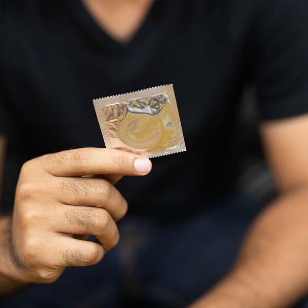 Man in a black shirt holding a condom