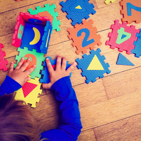 Young child at a daycare center playing with colorful foam puzzles with numbers and shapes 