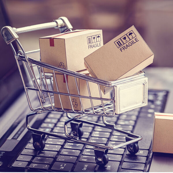 Little shopping cart with packages on top of a keyboard 