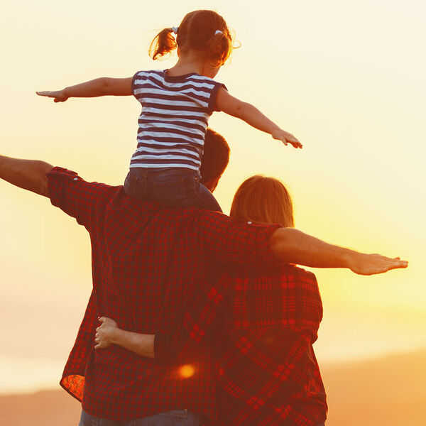 Dad, mom, daughter looking at the sunset 