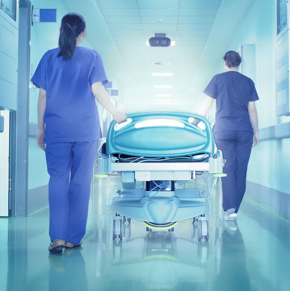 Two nurses pushing a hospital bed