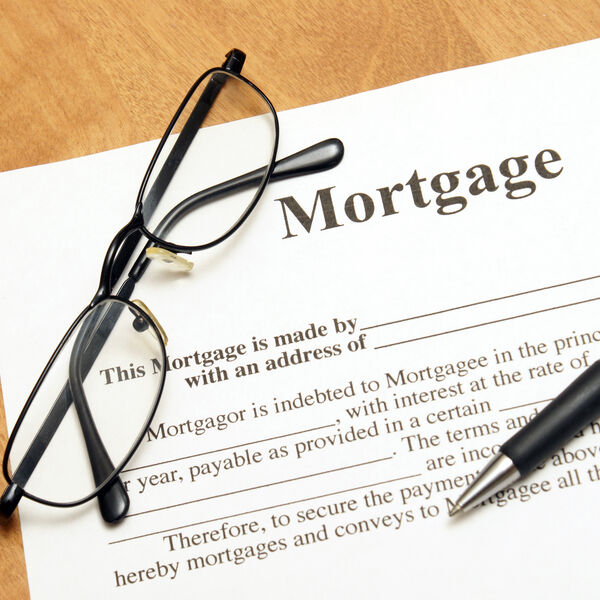 Mortgage contract with a black and silver pen and a pair of black glasses on top