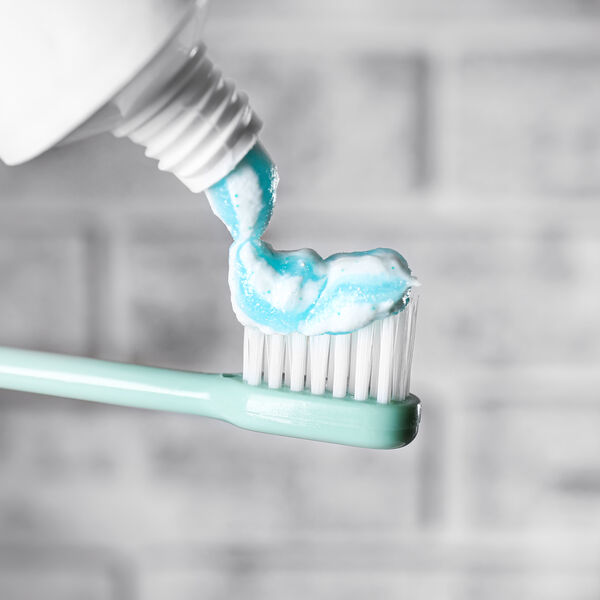 Toothpaste being added to light blue toothbrush