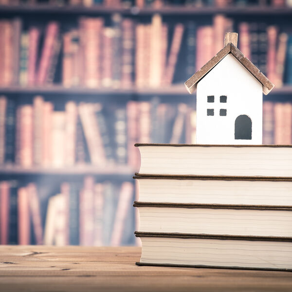 Little house on top of books with books on shelves in the background