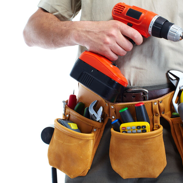 Handyman with tool belt filled with tools and a power drill in one hand