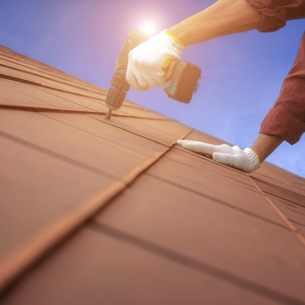 Roofer drilling into roof